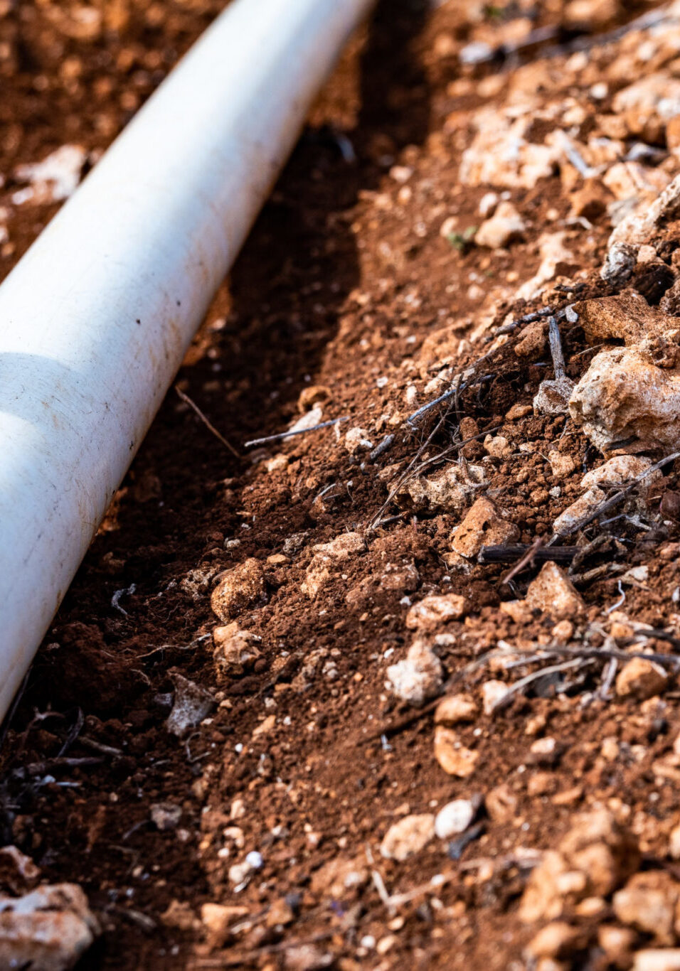PVC pipe in dirt trench outdoors for plumbing water drainage installation. Underground irrigation system.